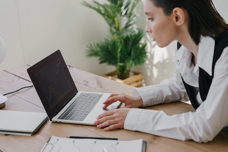 Uśmiechnięty specjalista marketingu pracujący na laptopie w nowoczesnym biurze.